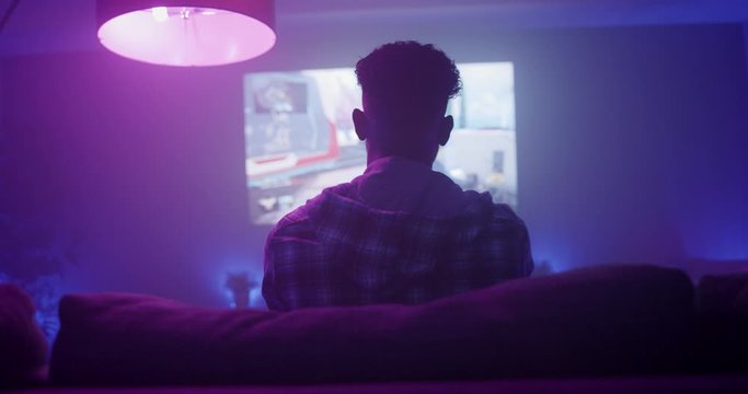 Man winning video games at night in apartment