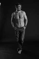 Obraz na płótnie Canvas black and white studio shoot of strong athletic man on dark background
