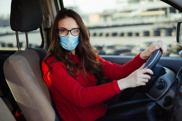 young woman in coronavirus mask sitting in car
