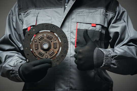 A car mechanic is showing an old car clutch disk close up.