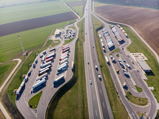 Top view of the parking of trucks, gas station and the route on which cars rush.