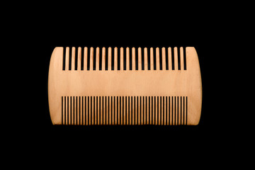 Wooden beard comb isolated on black background.