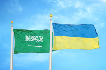 Saudi Arabia and Ukraine two flags on flagpoles and blue cloudy sky