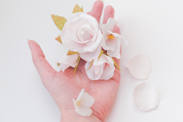 White flowers and delicate pink roses on a female hand on a white background