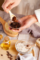 Concept of home beauty care and natural organic ingredients in cosmetology. Girl preparing homemade scrub with coffee, honey, oil, oat for gentle skin peeling and moisturizing.  Wooden background. 