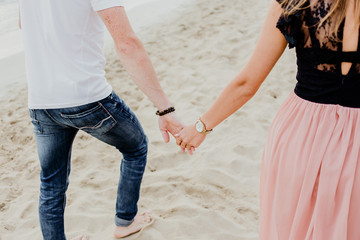 young couple holding hands on the beach