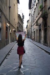 Fototapeta na wymiar Young woman walking on the street holding a map in Florence