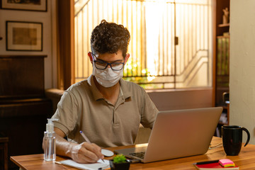 Hispanic with protective mask working at his residence. Home office concept.