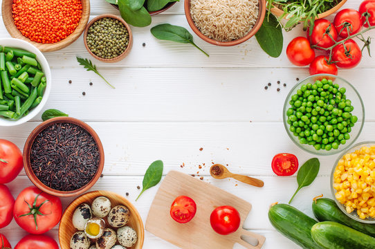 Frame Of Fresh Vegetables, Groats, Leafy Greens And Quail Eggs On White Wooden Background With Copyspace