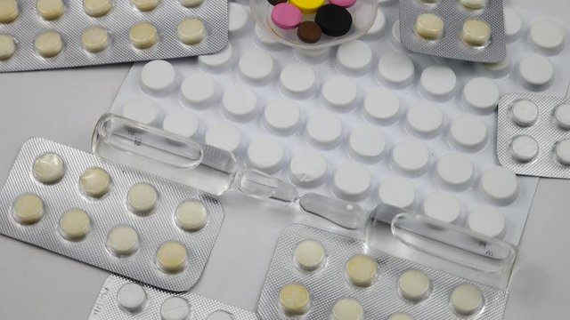 Pills in blister packs and glass ampoules with a drug are on a white background
