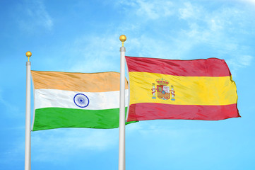 India and Spain two flags on flagpoles and blue cloudy sky