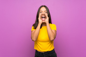 Young brunette girl over isolated background shouting and announcing something