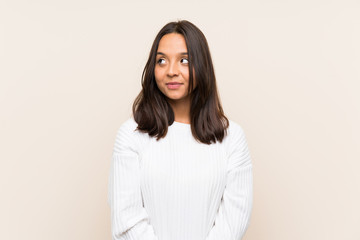 Young brunette woman with white sweater over isolated background standing and looking to the side