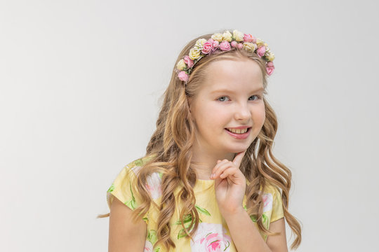 Partial Portrait Of A Young Teen Girl With Strong White Teeth Looking At Camera And Smiling, Finger Near Face. Closeup Of Little Smiling Girl On Isolated White Background