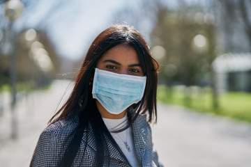 Girl putting on a protective mask to avoid contagion while walking down the street. Coronavirus...