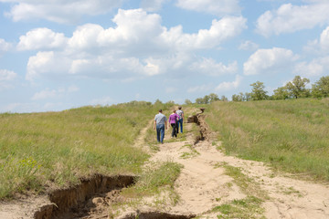 Obraz premium People are walking along country road on mild hill slope.