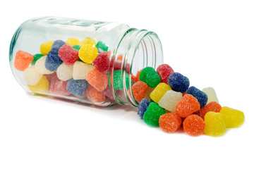 Colorful old fashioned spiced gumdrops spilling from a glass jar. Isolated.