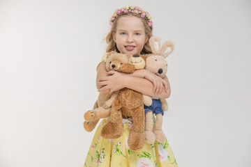 Girl holding bear and bunny with heart. White background