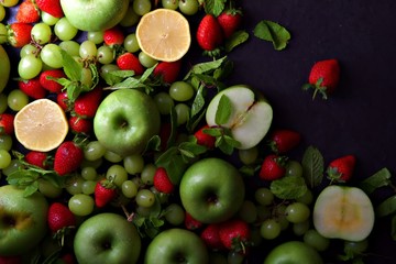 Naklejka na ściany i meble Fresh fruits including green apples, green grapes and red strawberries with lemon. Flat lay background.