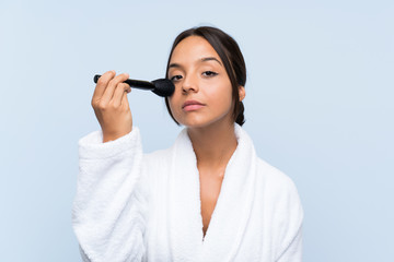 Young brunette girl in bathrobe with makeup over isolated blue background