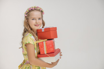 Portrait of blonde girl girl in pink dress and beautifully decorated hair carrying heavy gift boxes isolated on white background