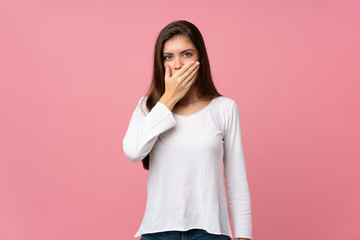 Young woman over isolated pink background covering mouth with hands