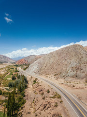 Andes Mountains, Cerro de los Siete Colores, Purmamarca Jujuy, Argentina colourful rock formation village and blue sky