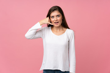 Young woman over isolated pink background making phone gesture. Call me back sign