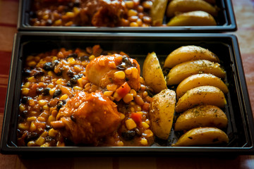 chicken with vegetables and potato wedges,in a disposable container,for delivery of food at home