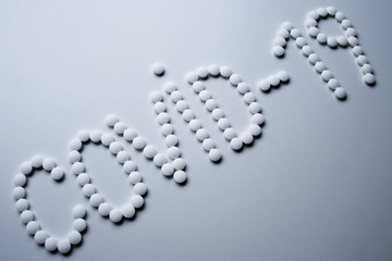 Text phrase Covid-19 sign concept made from white pills on a white background