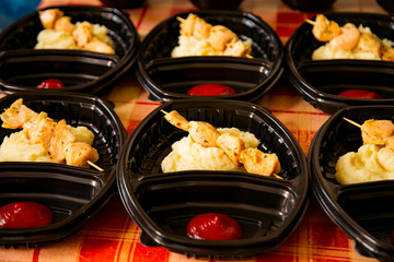 chicken kebab with a side dish in a disposable container,for delivery of food at home