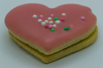 Close-up macro view of the edge of Christmas cookies in the form of a pink heart and its corpus in close up shot