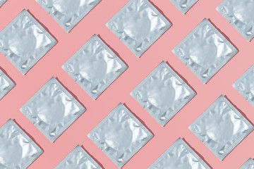 Pattern of silver condoms on a pink background. Stay home concept. Flat lay, top view.