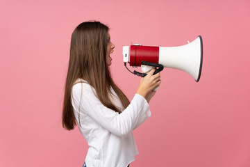 Young woman over isolated pink background shouting through a megaphone