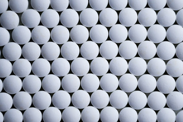 White tablets folded on a pharmaceutical factory production line close up pattern