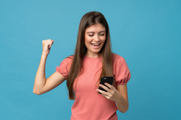 Young woman over isolated blue background using mobile phone