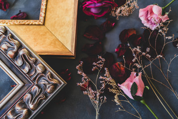 Corners of empty wooden picture frames and flowers on dark backdrop. Spring home decor concept.