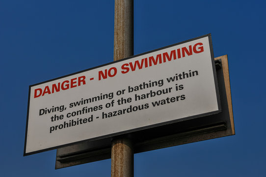 Sign at a harbour warning against swimming due to hazardous waters