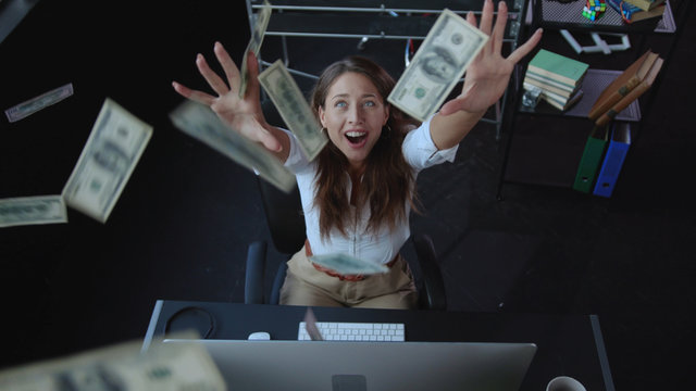 Excited happy young woman celebrating money rain fortune financial success rejoicing with high salary in the office. Payday. Instant success.