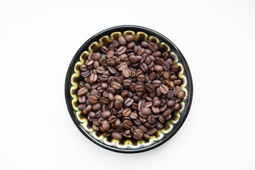 Natural coffee beans on a plate, nk white background. View from above.