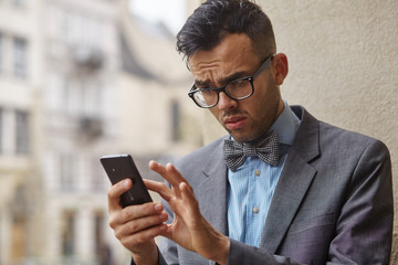 stylish man looking for something in his smartphone. he is concerned about what he has seen