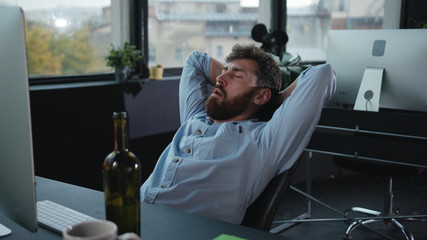 Fun office worker going crazy of alcohol lying on the floor and laughing hard. Drunk addicted...
