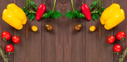Fresh vegetables like yellow bell peppers, cherry tomatoes, rosemary and parsley leaves. Healthy food frame on wooden background, top view with copy space