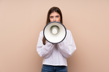Young girl over isolated background shouting through a megaphone