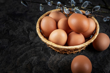 Fresh organic farm eggs lie in a basket on a stone plate, close-up, selective focus, shallow depth of field. Concept, healthy eating, spring religious holidays.
