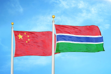 China and Gambia two flags on flagpoles and blue cloudy sky