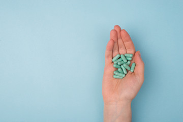 Top above overhead pov close up view photo of hands holding handful of pills isolated on blue background with blank copy empty space