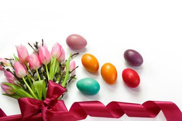 Easter background with colorful Easter eggs and a bouquet of tulips and catkins tied with a ribbon