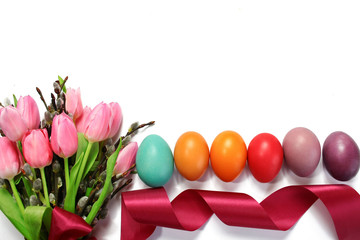 Obraz premium Easter background with pink tulips tied with a ribbon, catkins and colorful Easter eggs