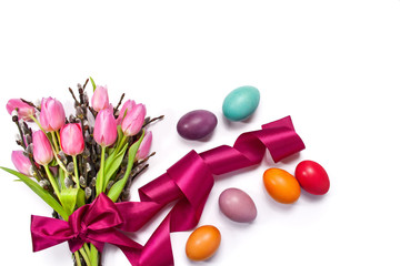 Tło wielkanocne z różowymi tulipanami przewiązanimi wstążką, baziami i kolorowymi pisankami